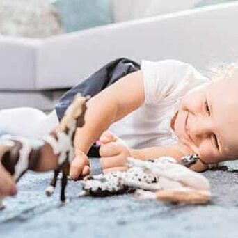 Niño jugando en el piso alfombrado con juguetes