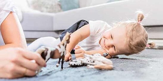 Niño jugando en el piso alfombrado con juguetes