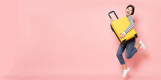 Woman holding yellow, hard-sided luggage