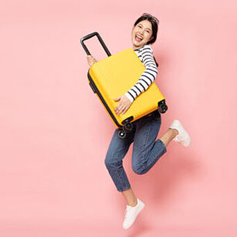 Woman holding yellow, hard-sided luggage