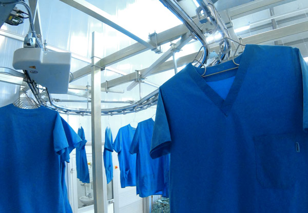 Uniformes médicos azules en perchas en lavandería industrial