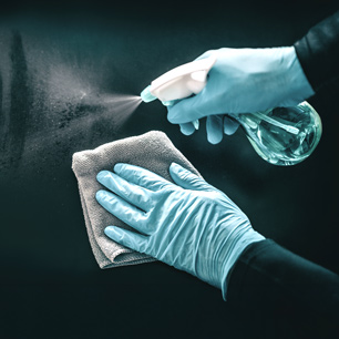 Manos con guantes inspeccionando la superficie del material tras exposición a desinfectante, usando herramientas de laboratorio