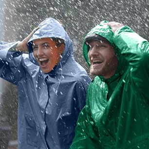 Mujer con impermeable azul y hombre con impermeable verde, protegiéndose de la lluvia intensa