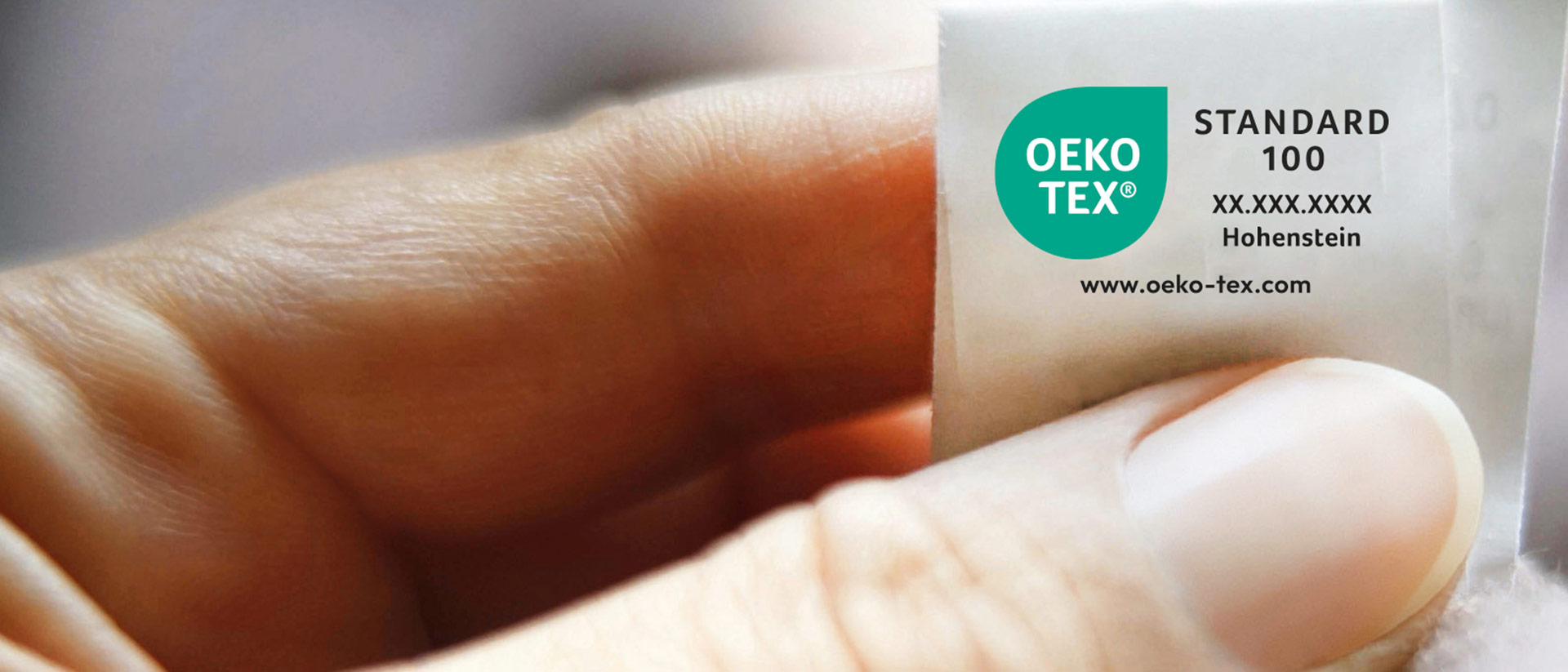 Mano sosteniendo un textil con la etiqueta cosida OEKO-TEX® STANDARD 100