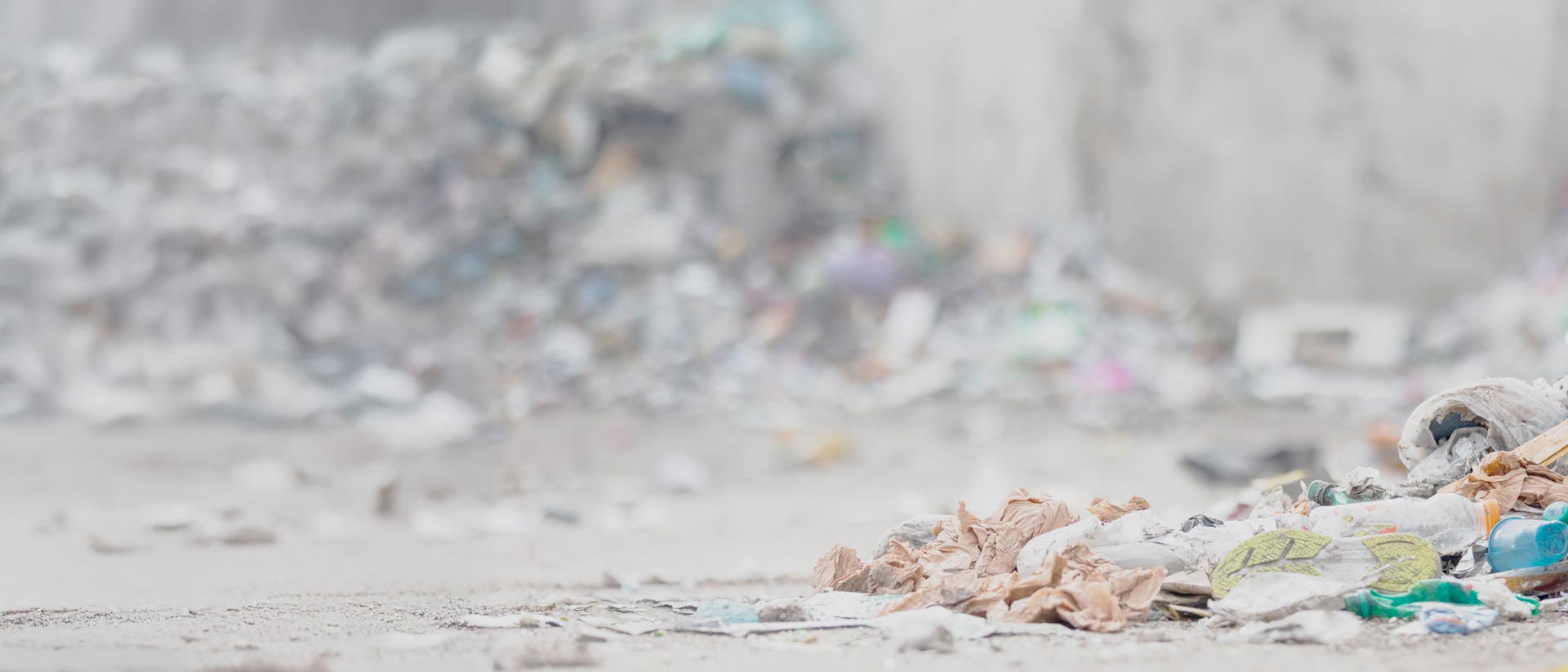 La EPR aborda los residuos de productos de corta vida útil Zapato, ropa y botellas de plástico desechados cerca de un gran montón de basura.