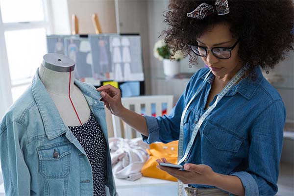 Diseñador trabajando con chaqueta de jean y vestido en busto