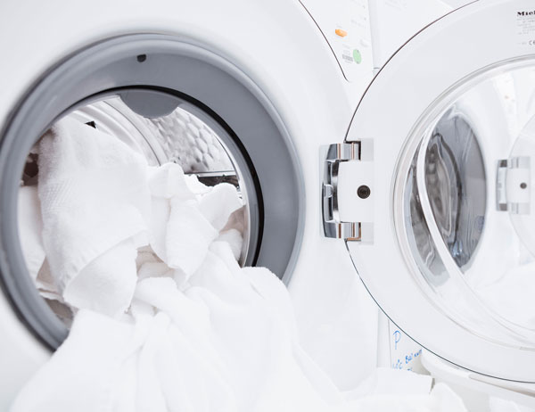 Prueba de la lavabilidad de los textiles Lavadora doméstica con puerta abierta y sábanas blancas