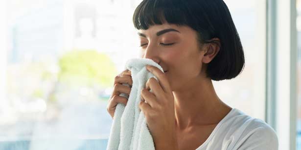 Mujer oliendo una toalla blanca y fresca