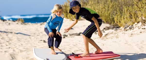 Muchachos en la playa vistiendo ropa de protección UV